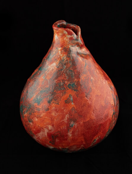 Váza kapkovitého tvaru s povrchovou úpravou vzájemně se prolínajících barevných glazur vrstvených štětcovou technikou.